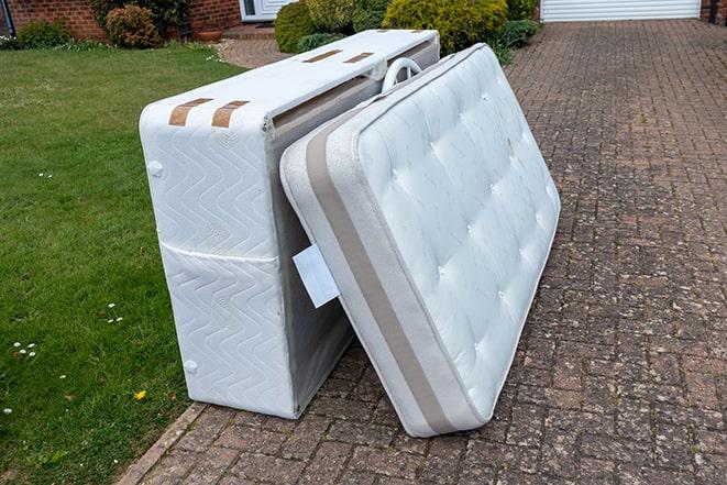 two workers lifting a mattress into a truck